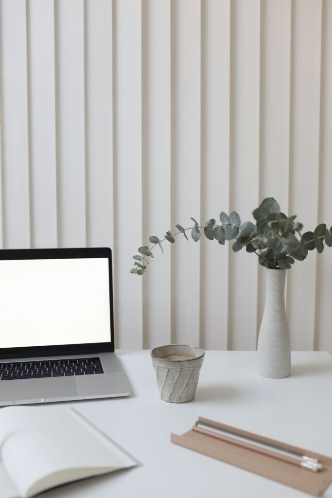 Escritorio minimalista con portatil, planta y taza de cafe, ilustrando el mantenimiento continuo de una pagina web
