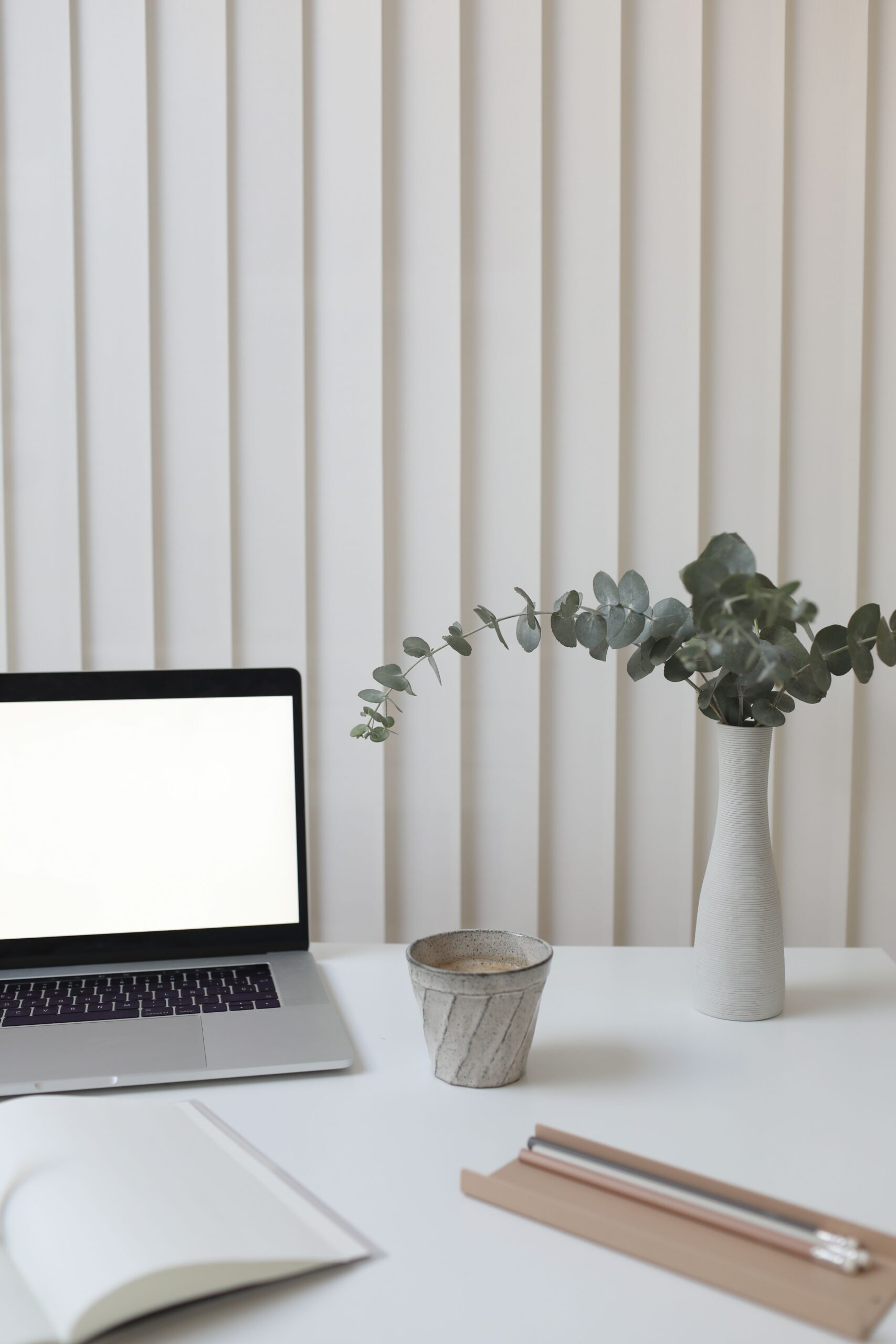 Escritorio minimalista con portatil, planta y taza de cafe, ilustrando el mantenimiento continuo de una pagina web